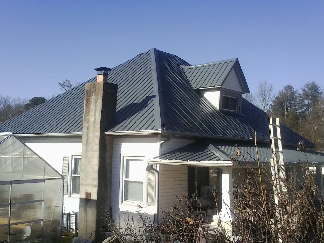 Dark blue standing seam metal roof on a white farmhouse with dormer — Slate & Tile Roof Repair by Roofing Brothers in Fort Gaines