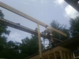 Carpenter setting a ridge beam over a new addition frame — Ice Dam Removal by Roofing Brothers in Fort Gaines