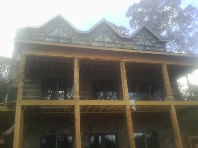 Dormers and porch framing on a large log home under construction — Roof Coating work by our crew in Fort Gaines