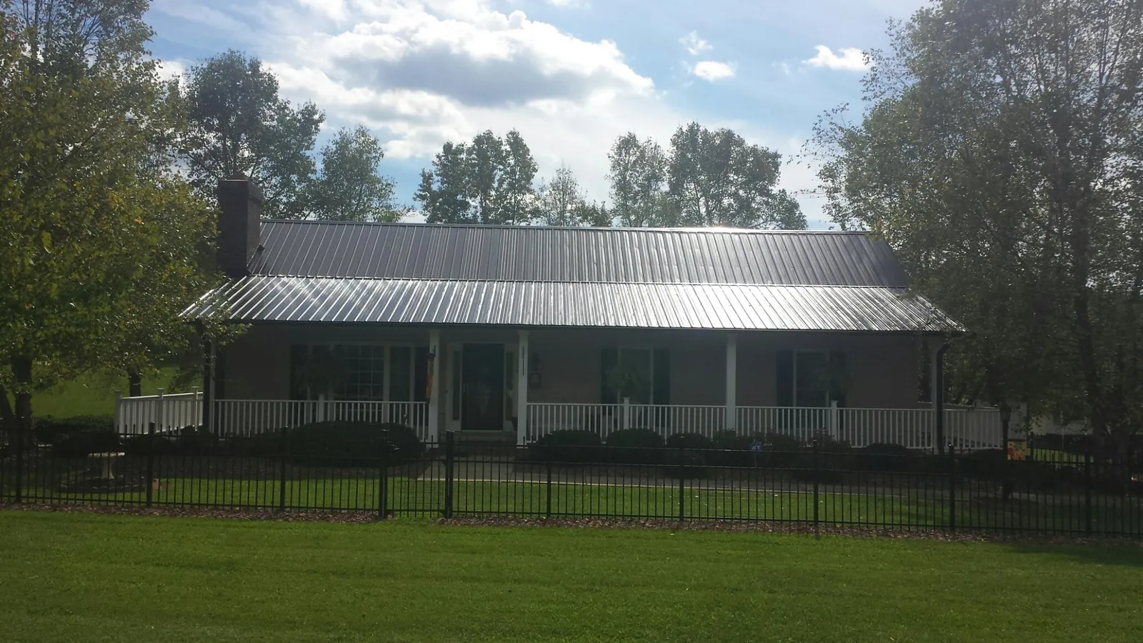Gray metal roof on a brick ranch with a full width front porch — Gutter Guard Installation work by our crew in Fort Gaines