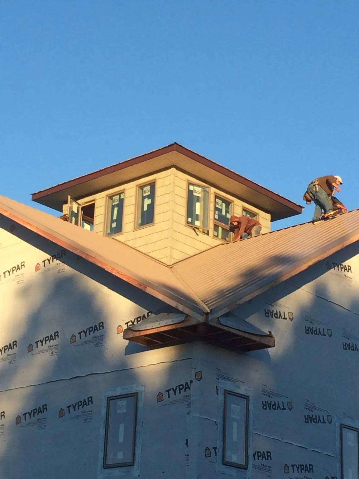 Roofers working around a rooftop cupola on a new metal roof at sunset — Roof Waterproofing in Fort Gaines by Roofing Brothers